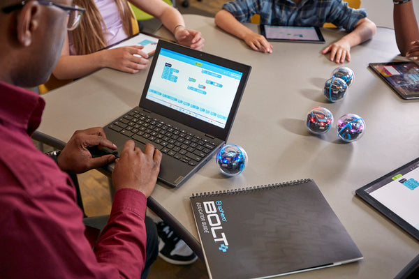 Students around a table code BOLT+ robots.