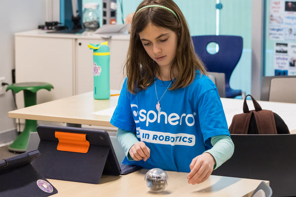 A girl learning STEM with a Sphero Bolt robot.
