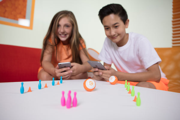 Two kids playing a bowling game using Sphero Minis.