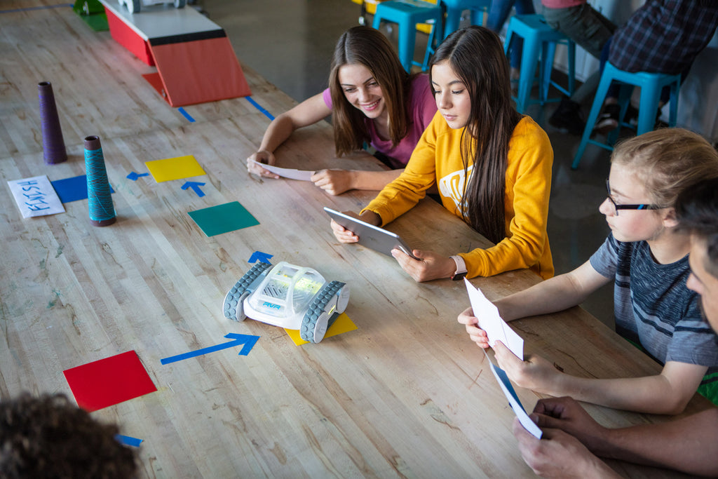 Three high school students work on a math activity with Sphero RVR robots.