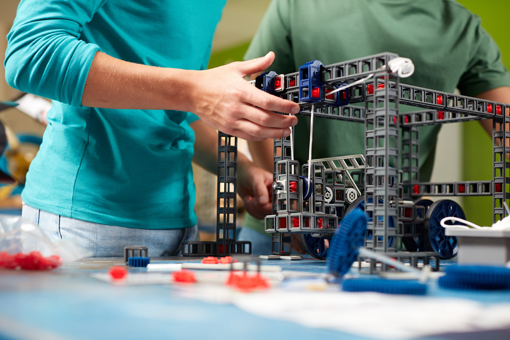 A student's hands building a model of a crane using Sphero Blueprint.