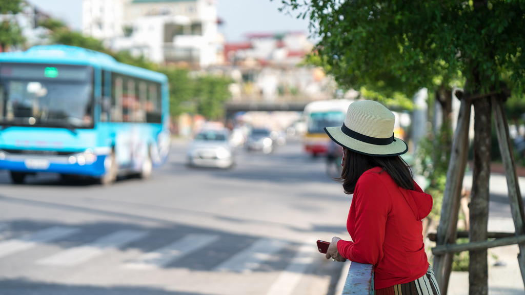 A woman waits for a bus. The schedule busses follow to make on-time arrivals and departures is an example of a real-world algorithm.