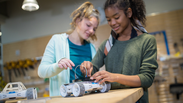 Two student girls building on top of Sphero Rover. 
